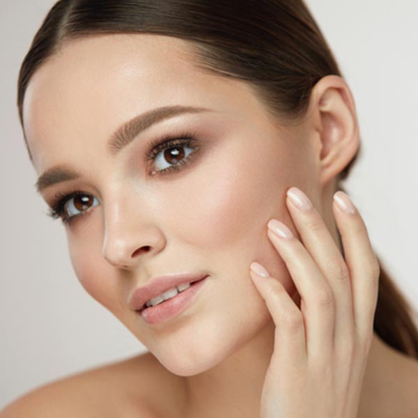 Woman examining her firm and youthful face after facial surgery.