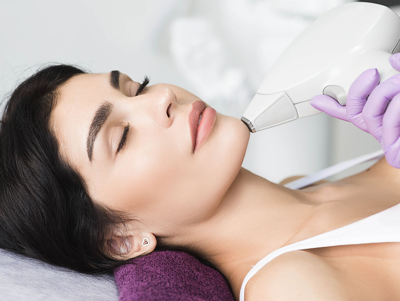 Woman receiving laser hair removal treatment around her chin.