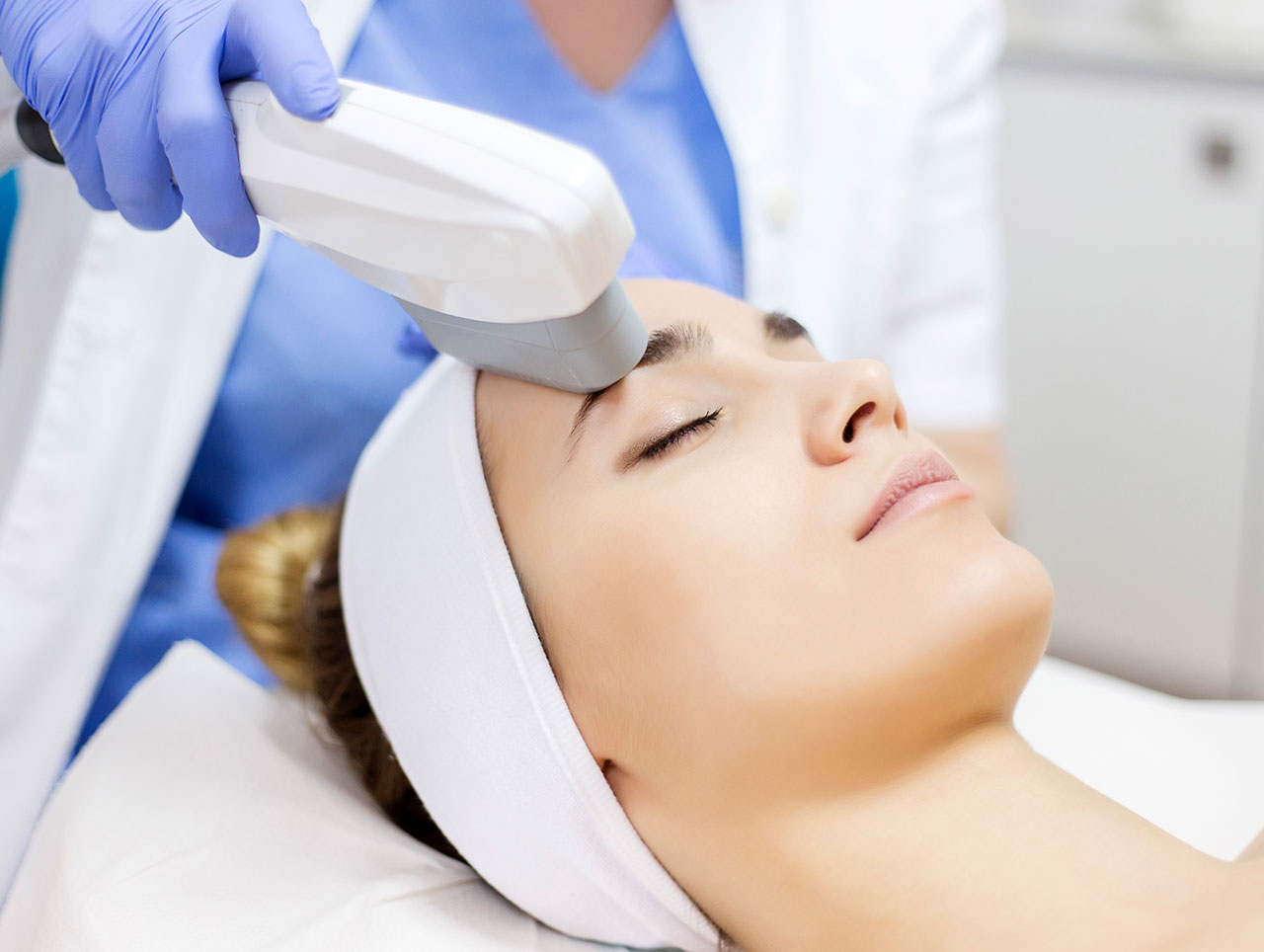 Woman receiving a photofacials treatment around her forehead.