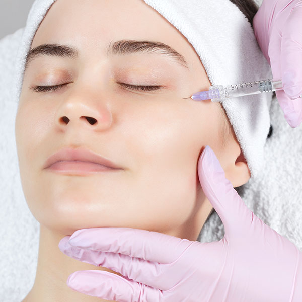 Woman receiving non-surgical Xeomin facial plastics treatment around her cheek and eye area.