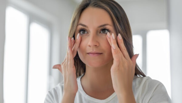 Woman looking in the mirror after blepharoplasty surgery